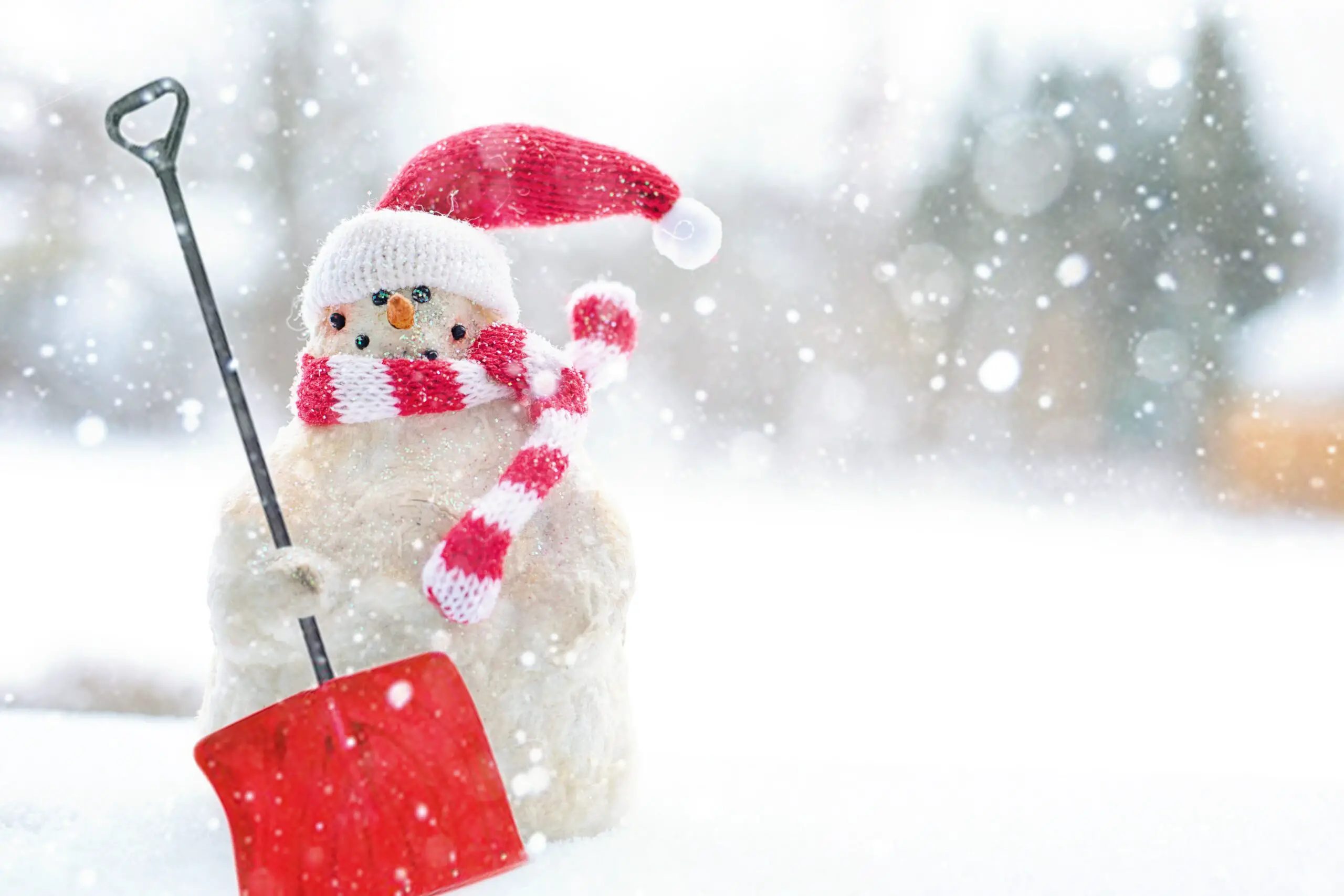 Ein gut verpackter Schneemann mit einer Schaufel in der Hand im Schneetreiben